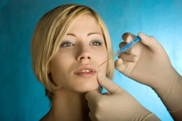 blonde female with short hair gets cosmetic surgery with needle in lip 